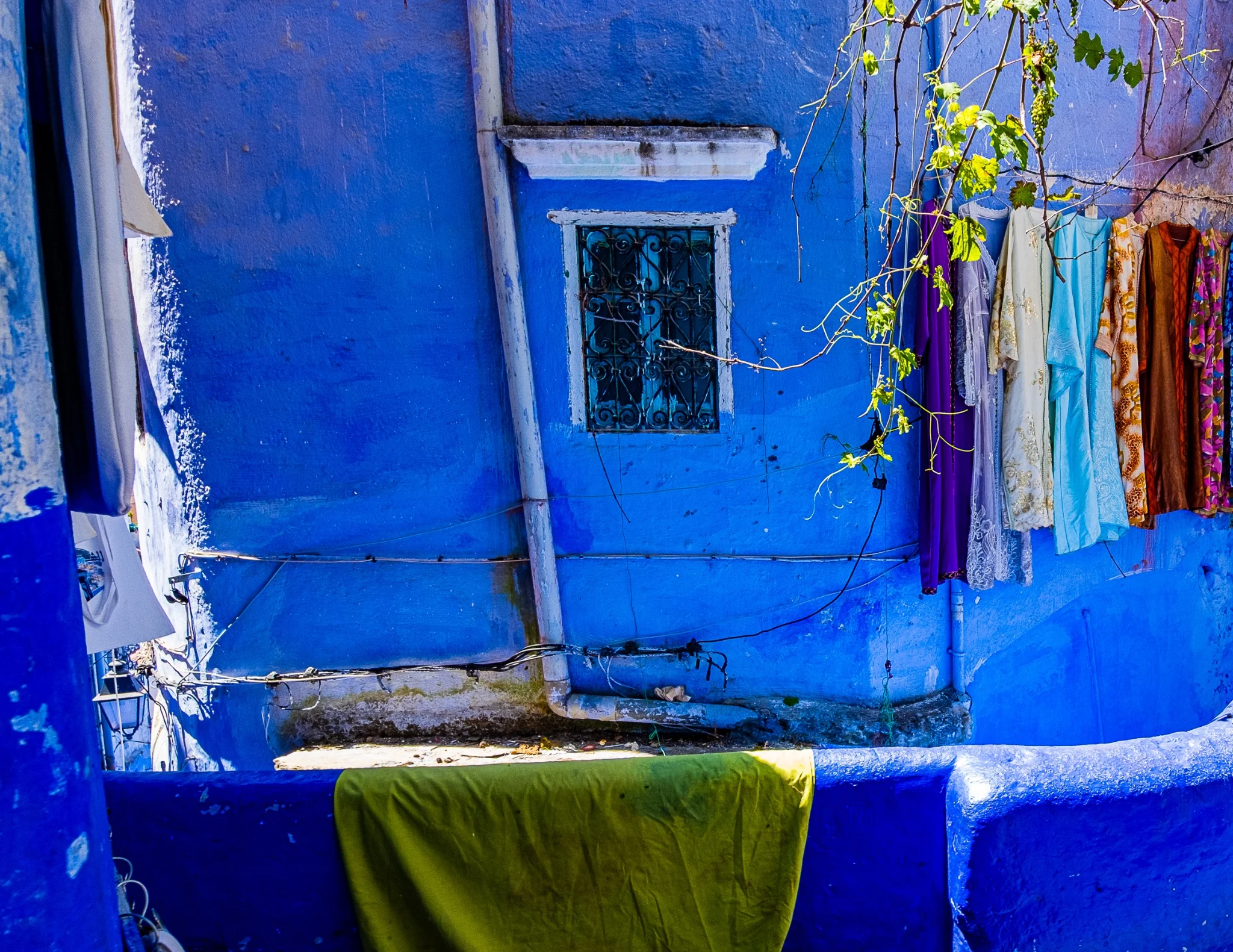 Linge coloré suspendu devant une maison bleue