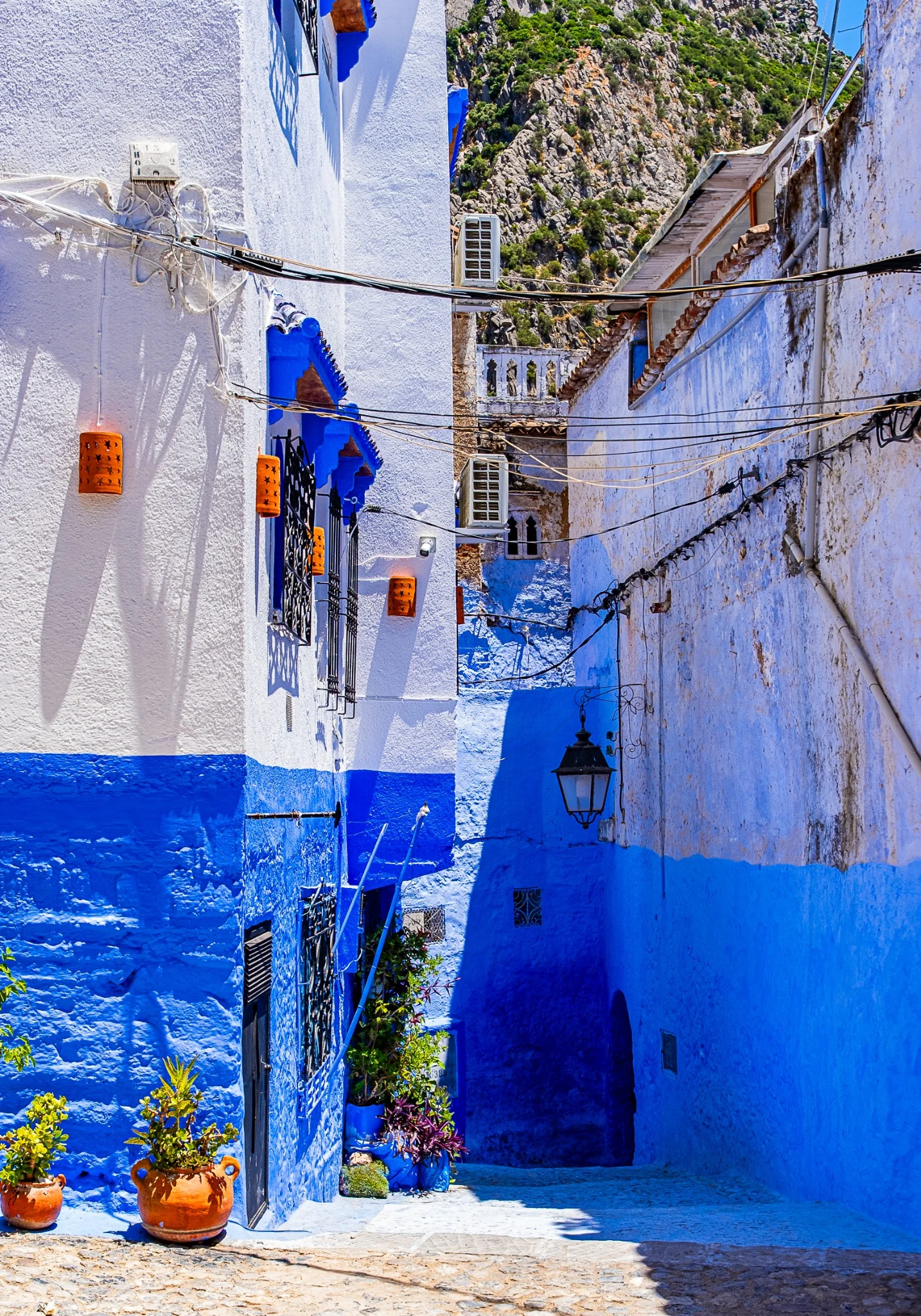 Ruelle blanche et bleue bordée de pots